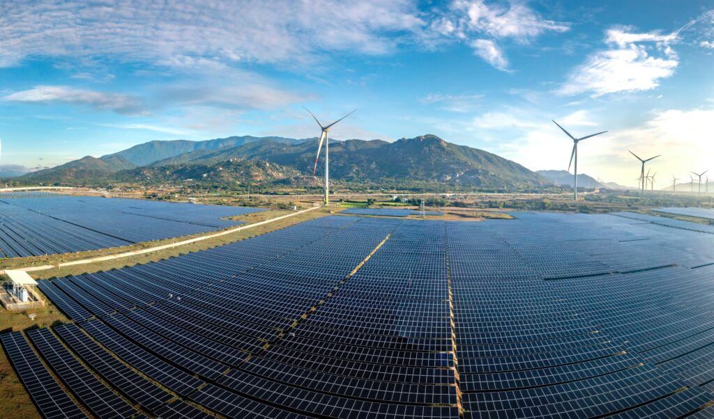 Une image montrant un mix énergétique renouvelable : barrage, panneaux solaires, éoliennes, réseau électrique